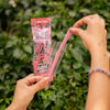 Person holding a Blazy Susan pink rose cone packaging with a green leafy background