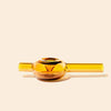 An amber glass water pipe with a spherical bowl and straight cylindrical mouthpiece by NWTN Home, shown on a solid light beige background.