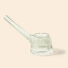 A clear ribbed glass water pipe by NWTN Home with a long angled stem, shown on a solid pale beige background.