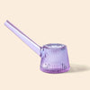 A NWTN Home translucent lavender purple glass water pipe with a ribbed, flared base and a long angled stem, shown on a solid pale beige background.