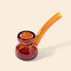 An amber glass water pipe with a double-bulb bowl and a curved stem by NWTN Home, shown on a solid light beige background.