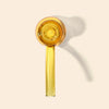 A translucent amber glass hand pipe with a matching straight glass stem, photographed on a warm off-white background with a soft shadow.